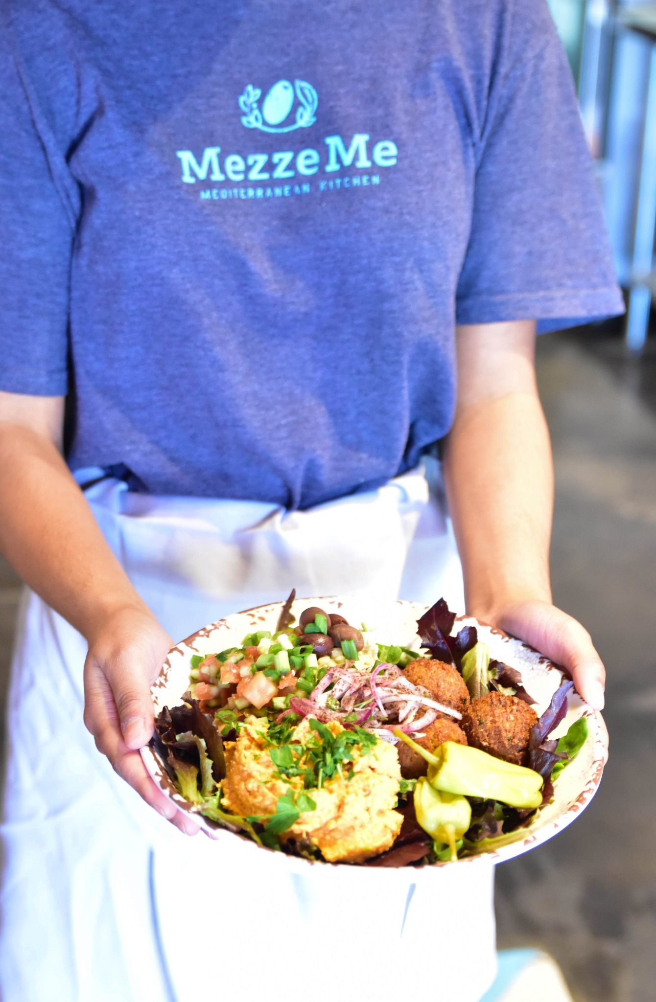 A MezzeMe team member presenting a freshly prepared plate